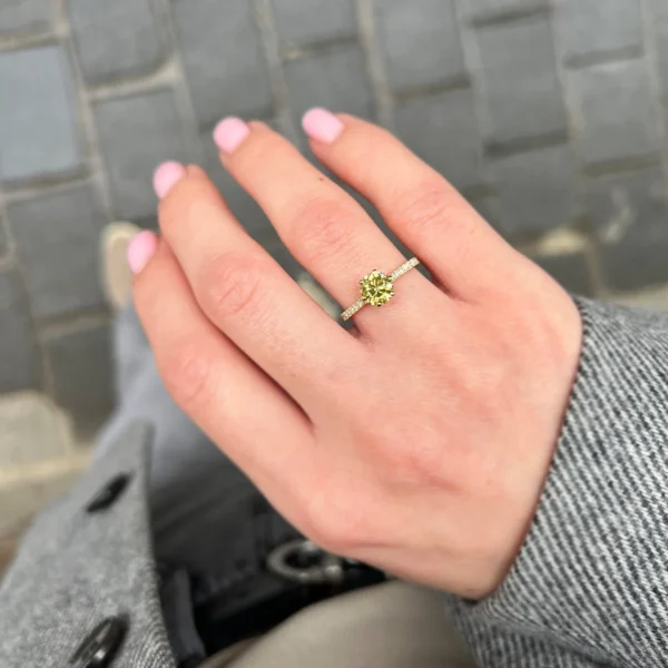 Hand shot of a 1 carat yellow diamond pavé engagement ring in 18k yellow gold with round yellow centre diamond and pavé diamond band.