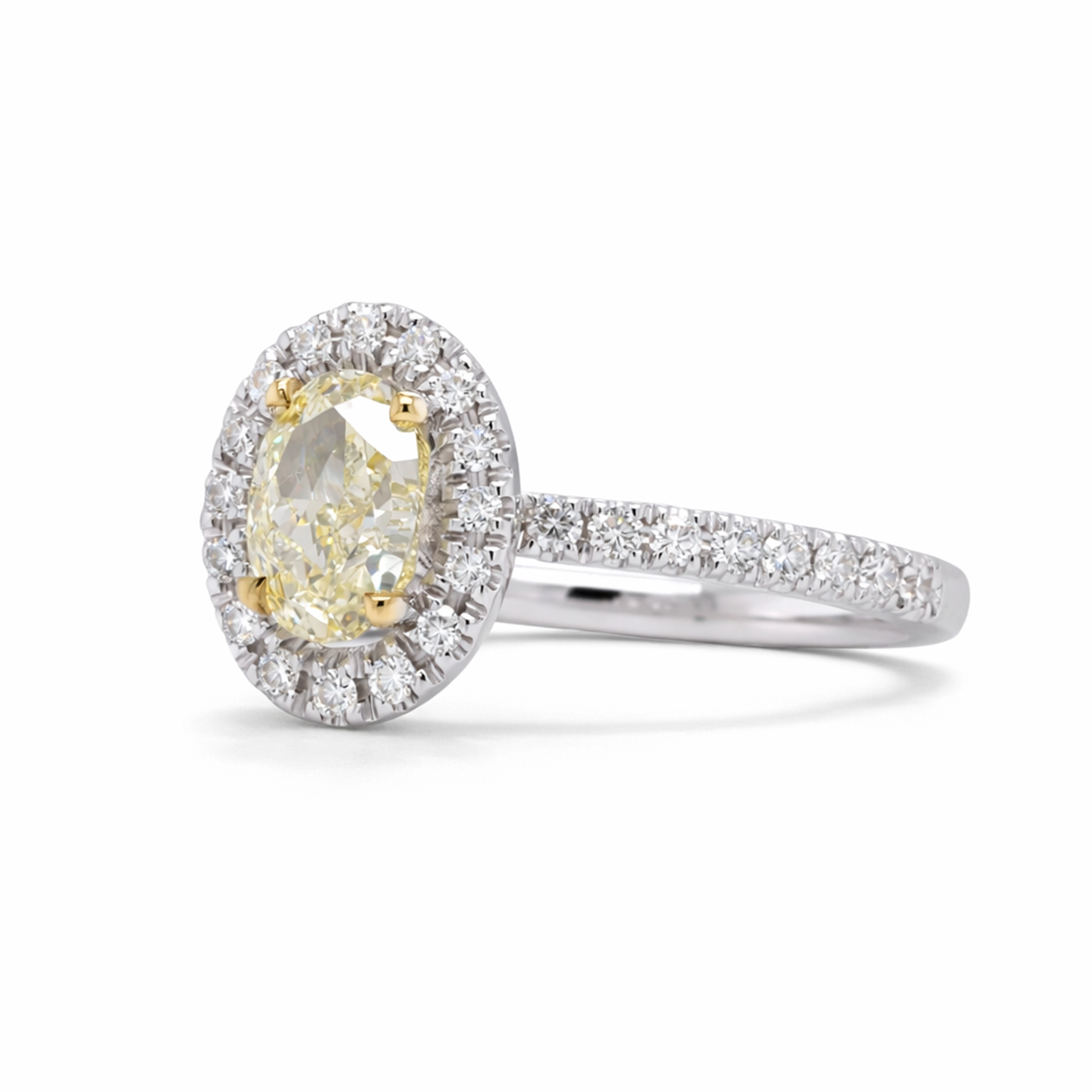 Bague Halo Diamant Jaune Ovale En Or Blanc 18 Carats Certifiée Gia 3 - Orogem Jewelers Vue En Angle D’une Bague Halo Diamant Jaune Ovale En Or Blanc 18 Carats Avec 0,27 Ct De Diamants Blancs D–F Vs Autour De La Pierre Centrale Et Sur L’anneau.