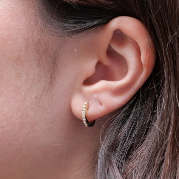 Petites créoles en or jaune 18k serties d’une rangée de diamants taille brillant, présentées de face et de côté.