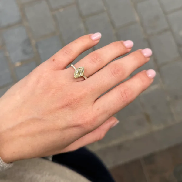 Hand met marquise geslepen gele diamanten halo ring in 18K geelgoud.
