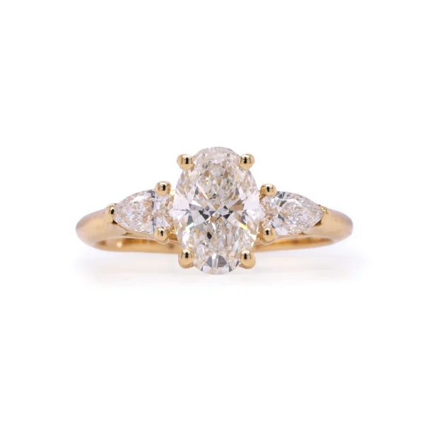 Front view of 18K yellow gold ring with 1.04 ct oval GIA-certified diamond and 0.28 ct pear-shaped side diamonds.