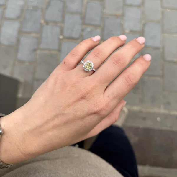 Elegante hand met 1.50 ct cushion-cut Fancy Light Yellow diamant ring in 18k witgoud, van bovenaf gezien.