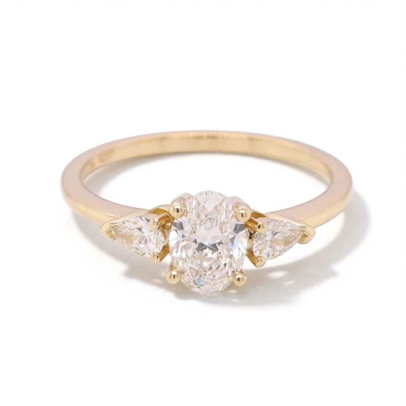 Angled View Of 0.73 Ct Oval Diamond Ring With Pear Sidestones In Yellow Gold.