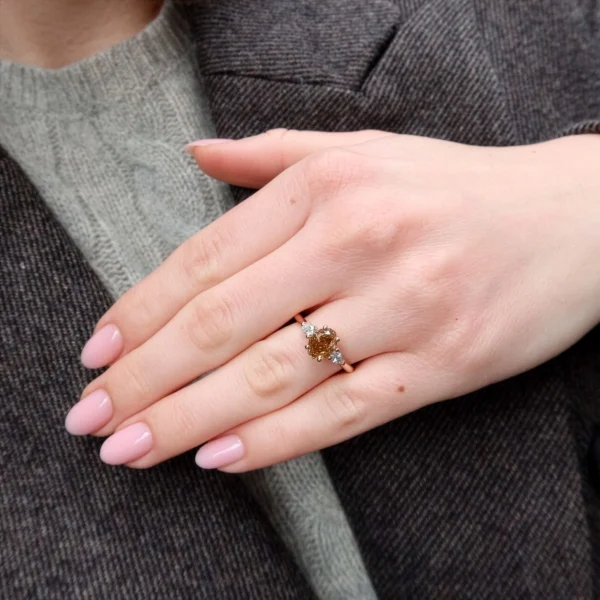 Close-up of rose gold diamond ring worn with neutral outfit