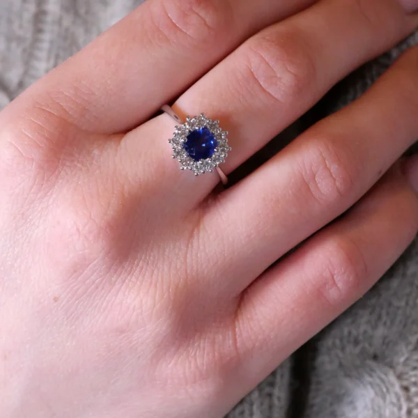 Gros plan bague saphir halo portée sur main montrant les détails des diamants