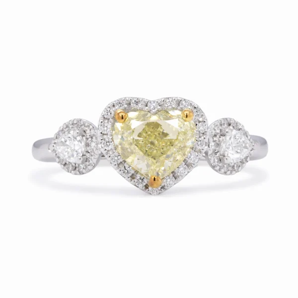 18k white gold three-stone halo ring with a 1.01 ct GIA-certified Fancy Light Yellow heart-shaped diamond, pear-shaped side diamonds, and halo diamonds around all three stones.