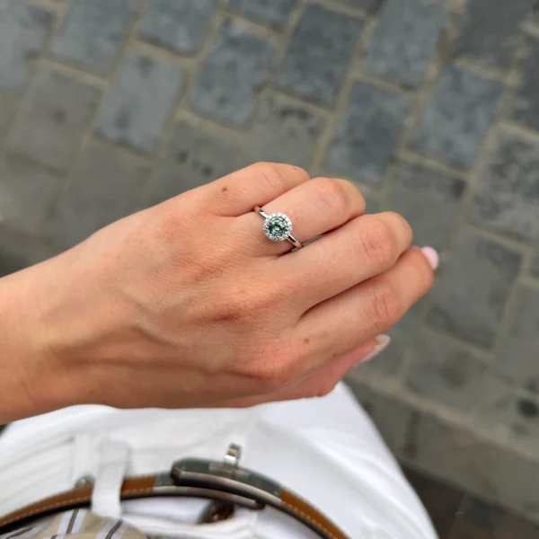 Groene saffier halo ring gedragen aan de hand in 18k witgoud met ronde natuurlijke saffier en diamanten halo.