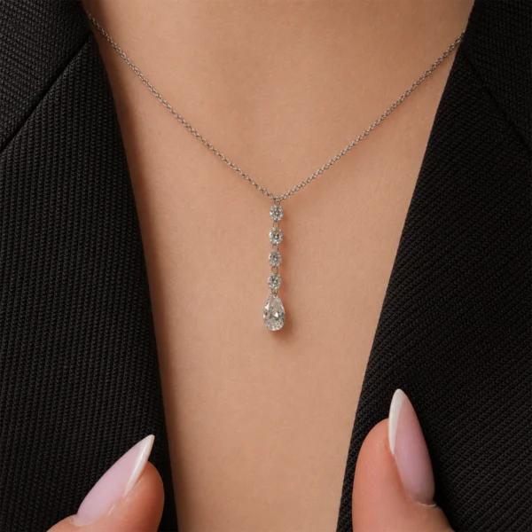 Pendentif diamant poire en or blanc 18 carats porté au cou avec quatre diamants ronds brillants au-dessus d’un diamant poire suspendu.