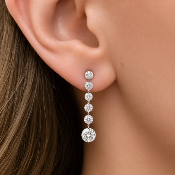 Boucle pendante diamants ronds en or blanc 18 carats portée à l’oreille avec cinq diamants ronds plus petits au-dessus d’un rond brillant suspendu de 0,50 ct.