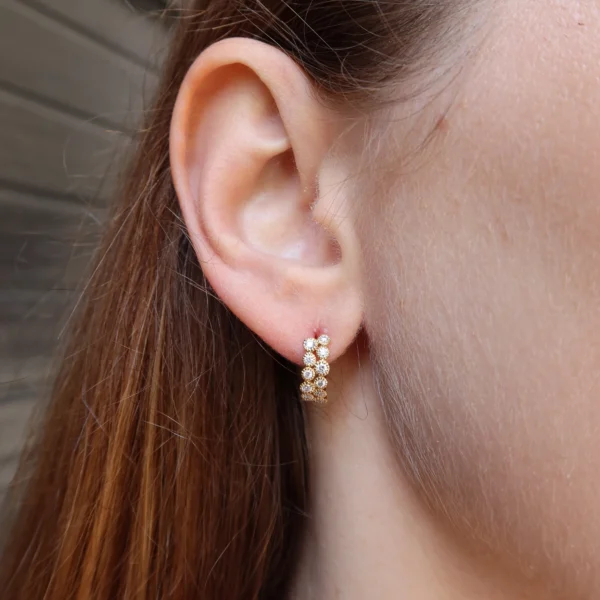 Diamanten ear climber oorbellen in 18k geelgoud gedragen aan het oor met oplopende ronde natuurlijke diamanten en een slank verticaal silhouet.