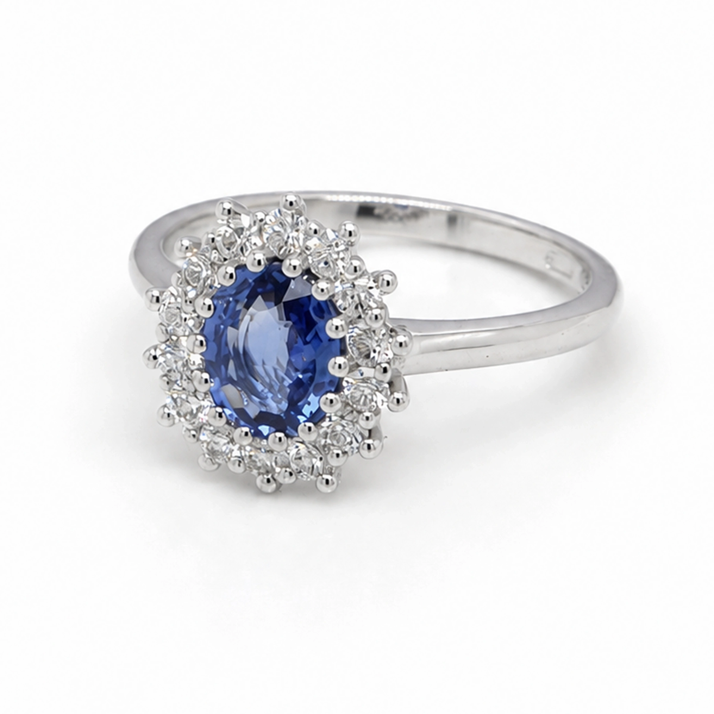 Oval Sapphire Halo Ring In 18K White Gold With 1.01 Ct Sapphire Center1 Angled View Of An Oval Sapphire Halo Ring With A 1.01 Ct Blue Sapphire And 0.36 Ct D-F Vs Diamonds.