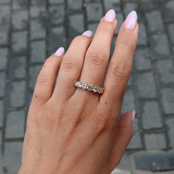 Seven stone diamond band in 18k yellow gold worn on the hand with a continuous row of round brilliant diamonds.
