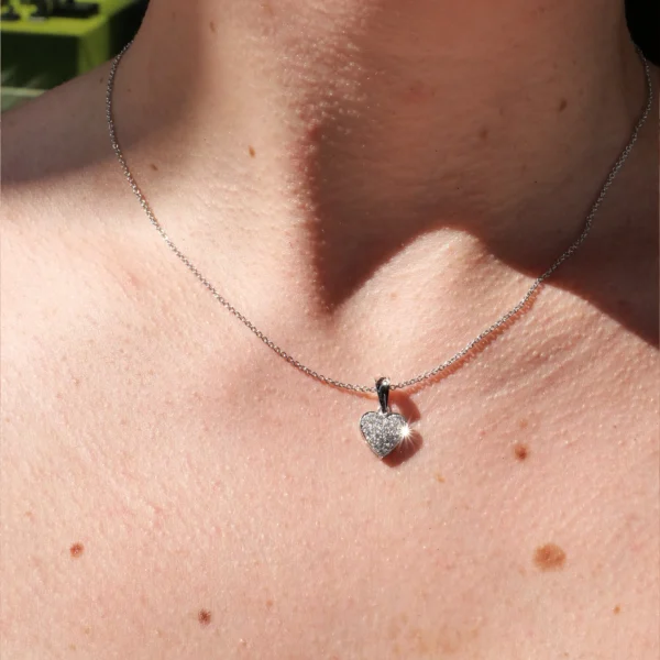 Witgouden pavé hartjesketting gedragen rond de hals met een volledig met diamanten bezette hartvormige hanger.
