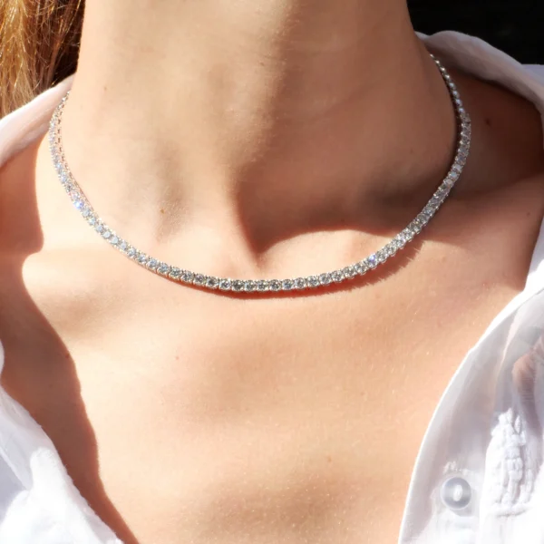 Vrouw die de diamanten tennisketting van 43 cm net boven het sleutelbeen draagt in natuurlijk licht.