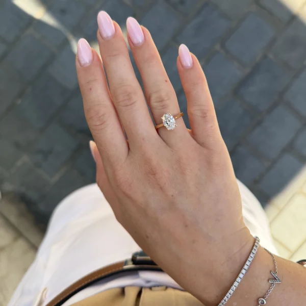 Ovale lab-grown diamant solitaire van 1,58 ct gedragen aan de hand met gepolijste 18k geelgouden band en viergriffenzetting.